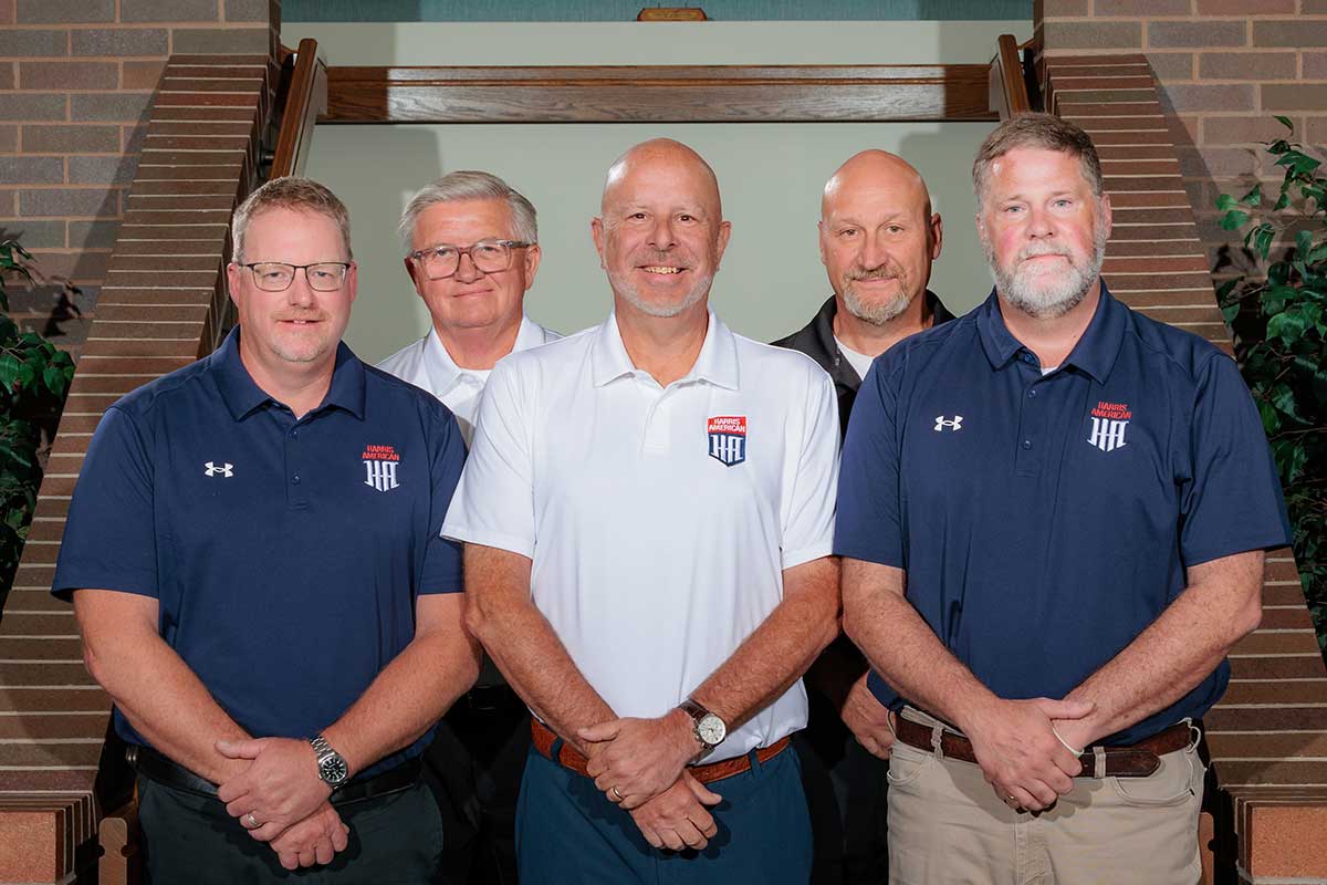 Five Men In Blue Shirts And White Polos Standing Together.
